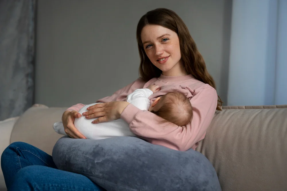 Mother breastfeeding newborn baby while sitting comfortably on couch at home