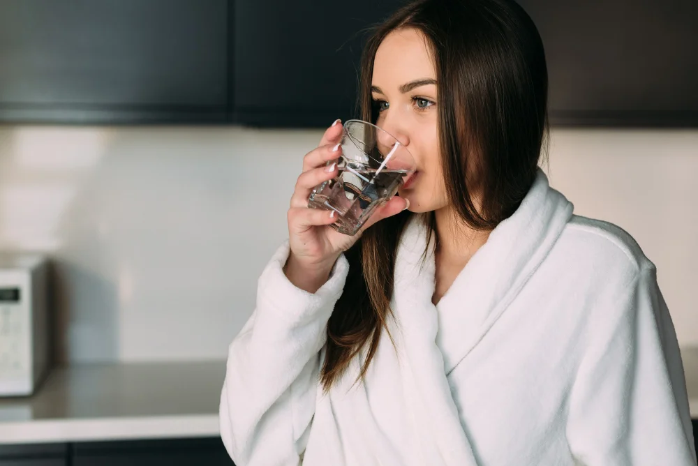 Woman drinking water for skin hydration and natural brightening glow