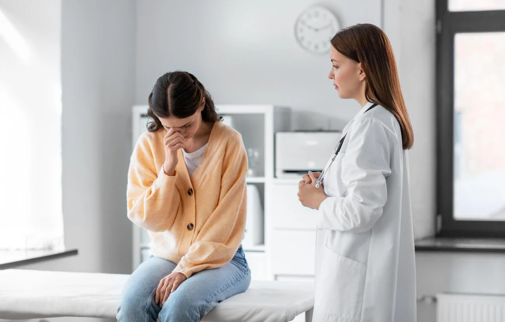 Embarrassed patient covering face during dermatology consultation with supportive doctor in medical office