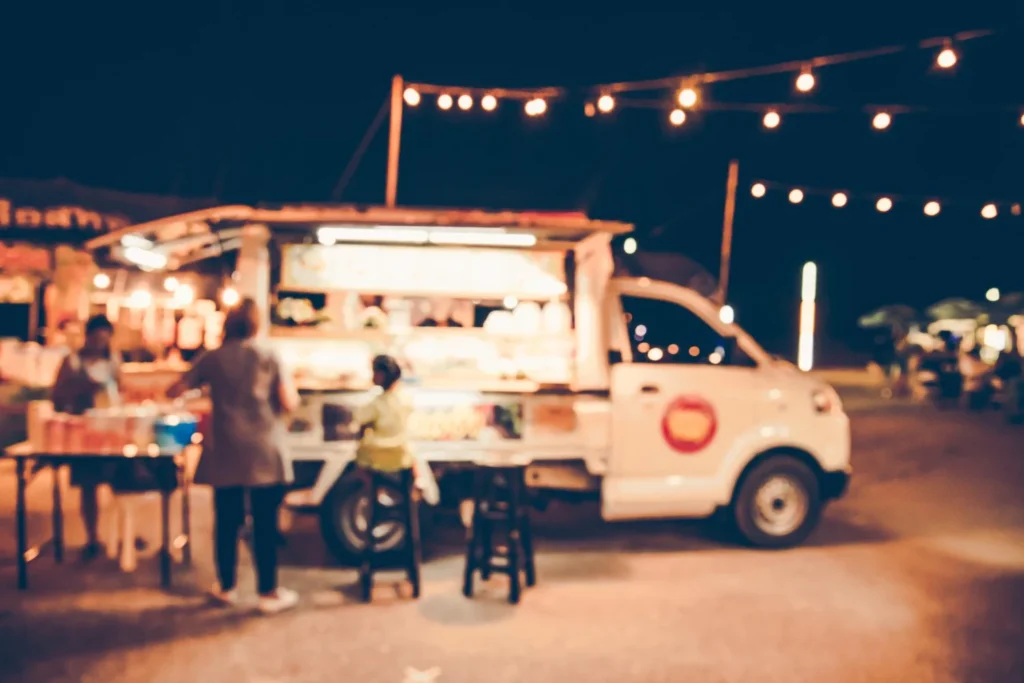 Evening food truck scene with string lights and outdoor seating at Tampa street food venue serving chicken and seafood dishes