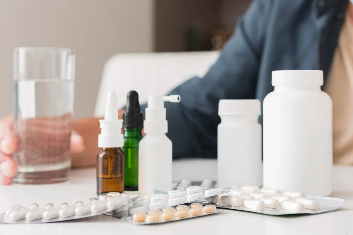 Comparison of dark spot correcting glow serum price in Pakistan versus glutathione tablets showing skincare products, supplement bottles, and pills on table with person in background
